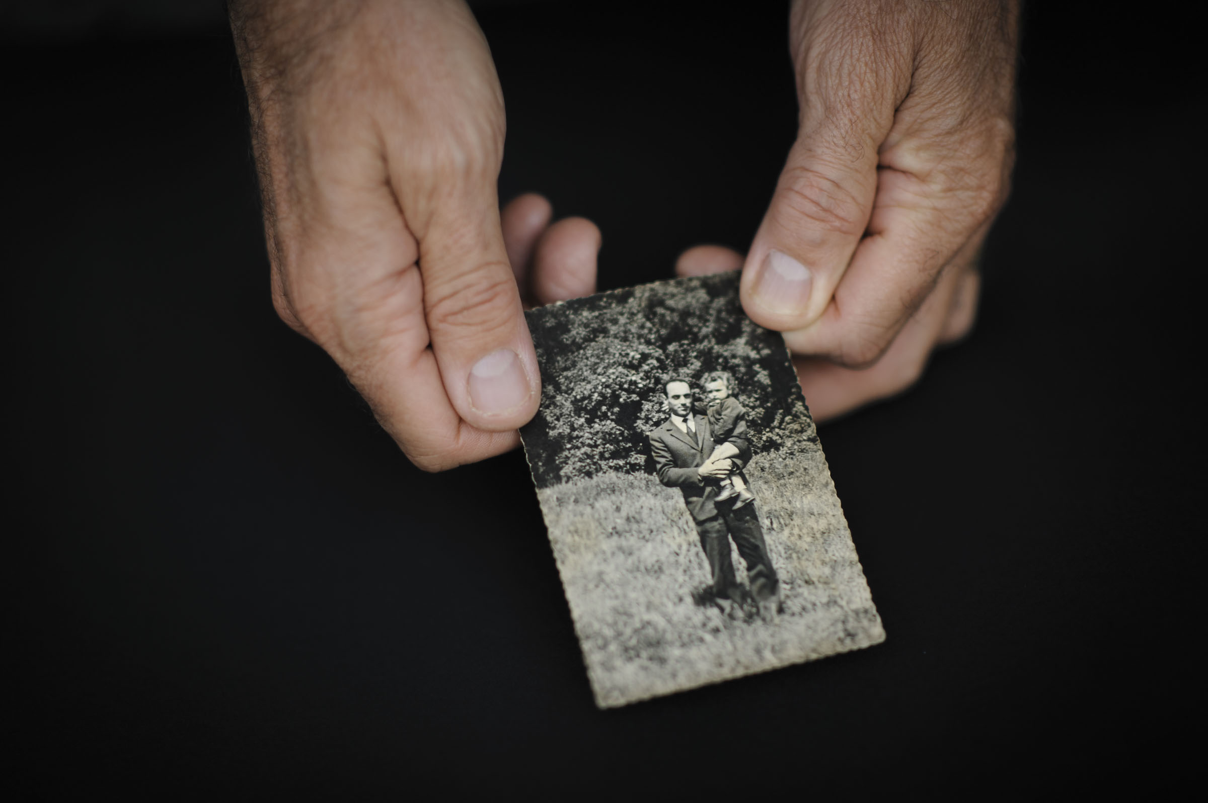 Two hands holding a photo of father and son.