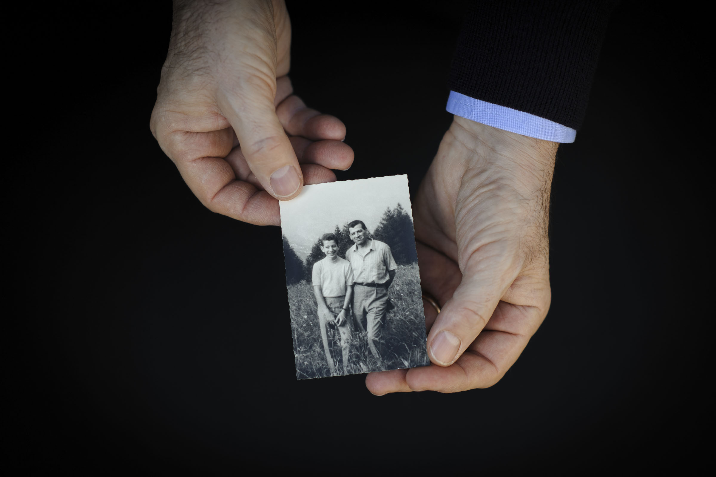 Two hands holding a photo of father and son.