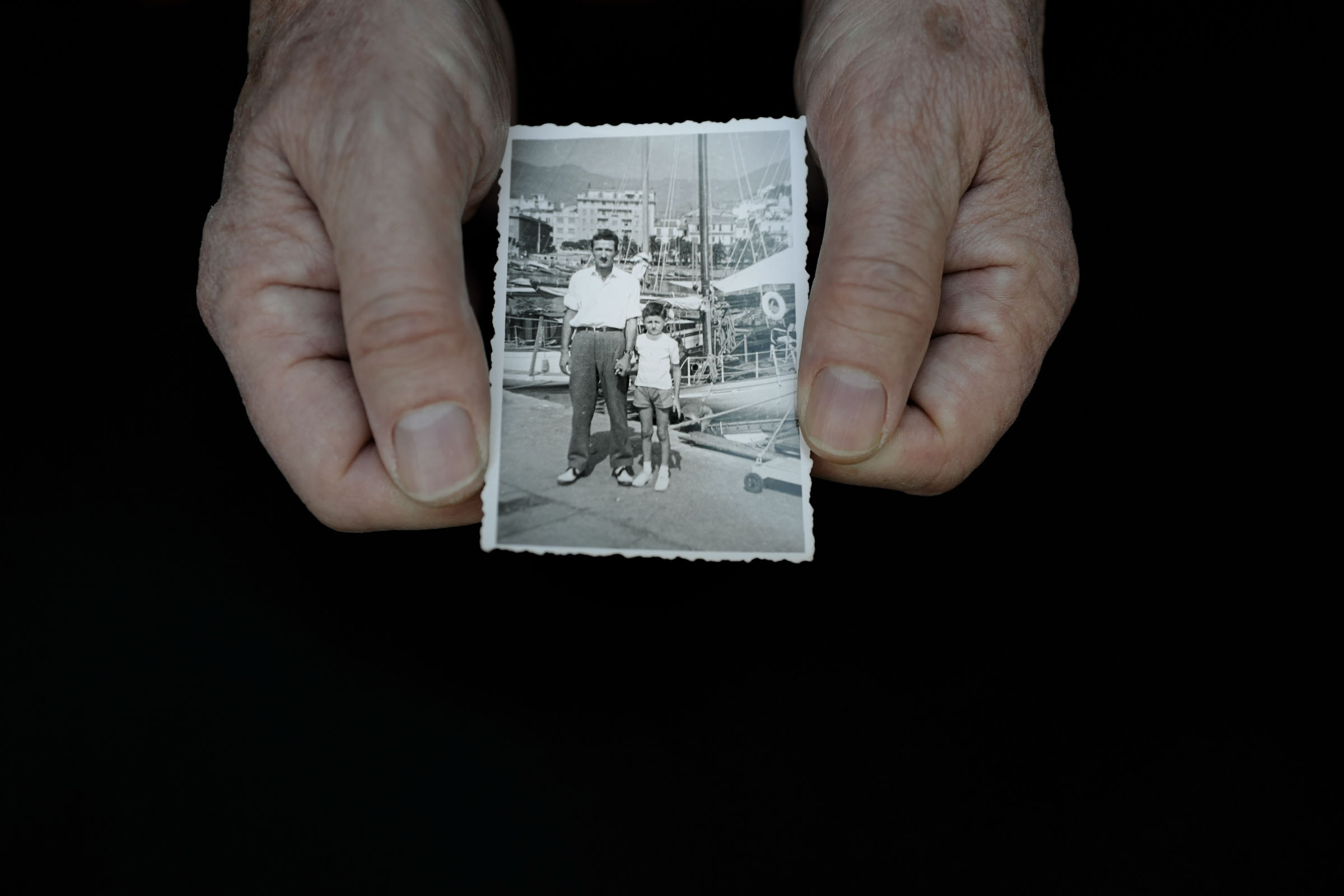 Two hands holding a historic photo of father and son.