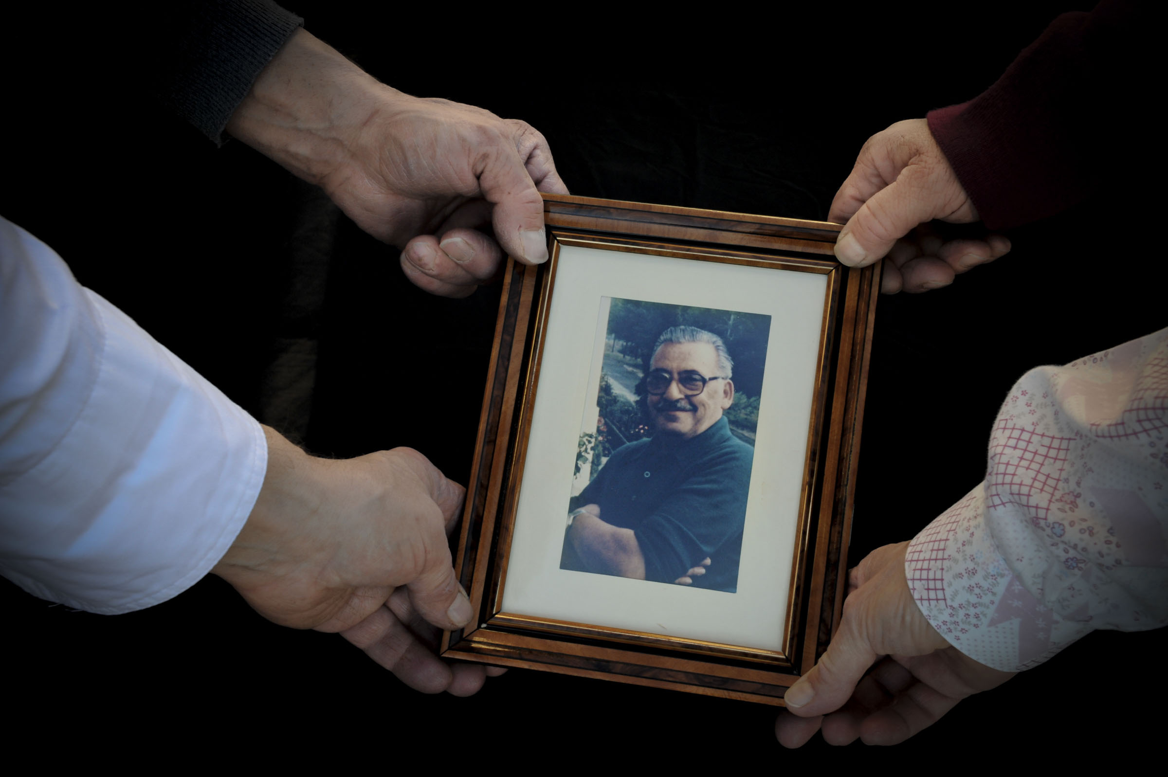 Four hands holding a framed photo