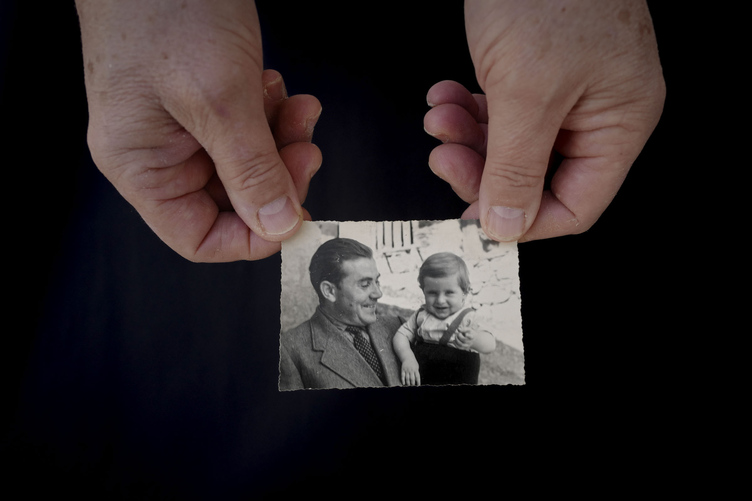 Two hands holding a historic photo of father and son.