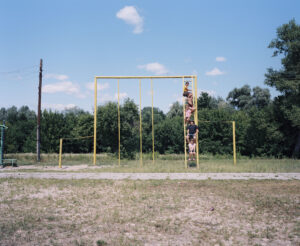 Five children sitting on the ladder of a climbing frame.