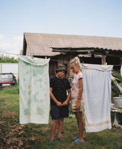 Mother and son standing behind a washing line on which two towels are hanging next to each other.