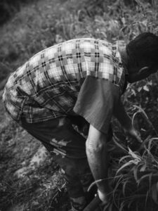 A man bending over as he works in the garden.