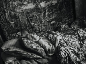 Oleksandra Havriš lying on her bed with several pillows and a blanket.