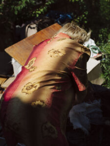 A blonde woman can be seen from the back bending over to pick something up from the ground.