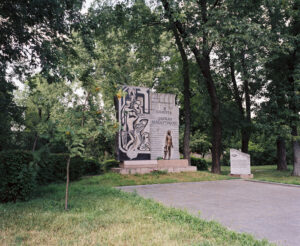 A memorial consisting of a stone plaque, a statue, and a text panel.