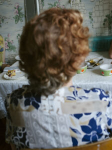 A woman seen from the back sitting at a laid table.