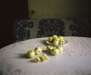 Apples lie on a table covered with a white embroidered tablecloth.