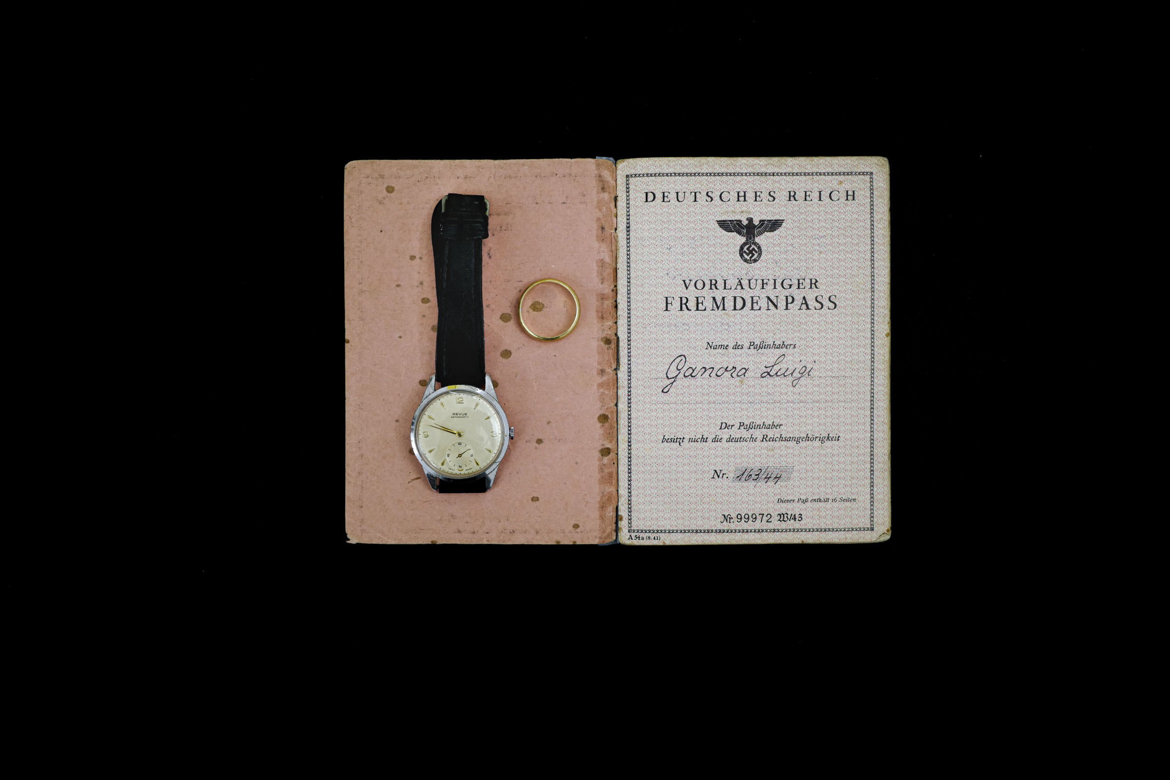 A watch and a ring lying on a historic ID document.