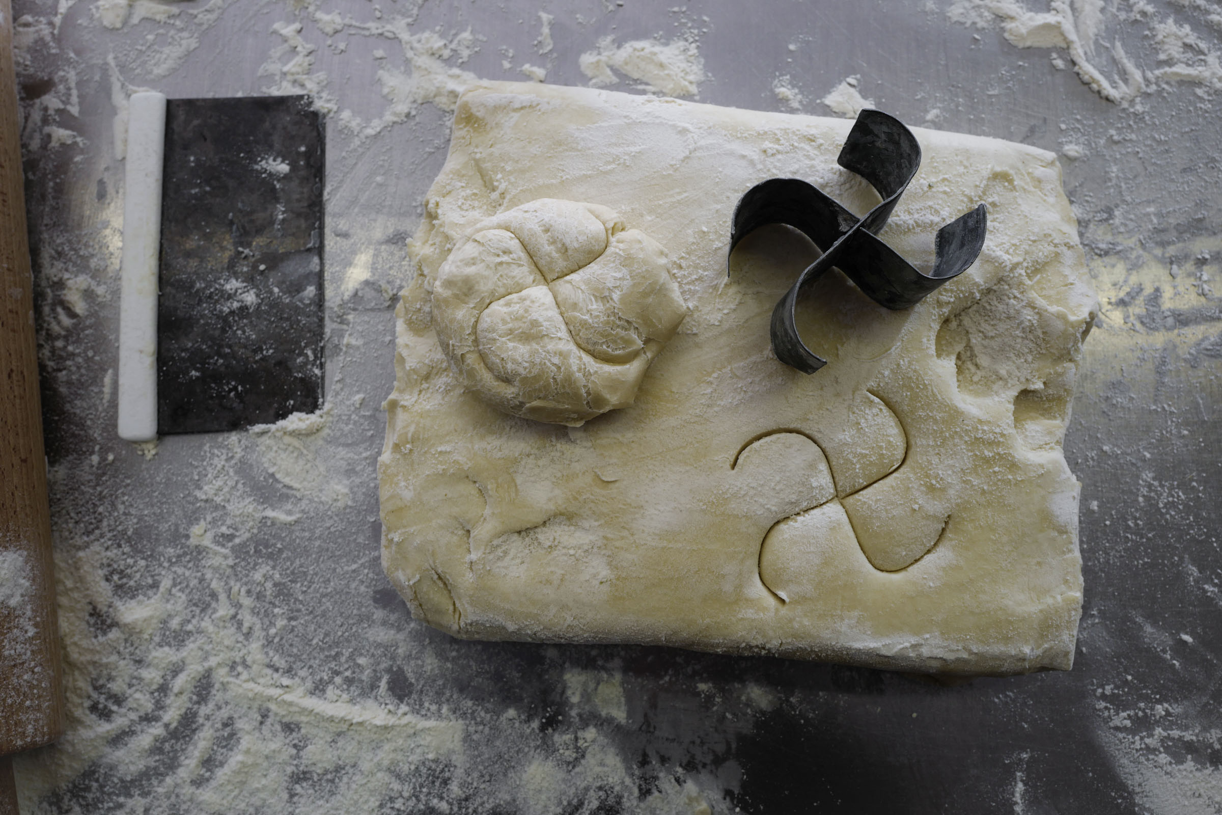 A shaped roll and a baking cutter on a piece of dough.